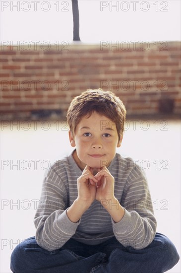 Cute young boy sitting cross legged. Photo : Fisher Litwin