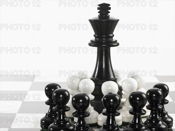 King surrounded by pawn chess pieces. Photo : David Arky