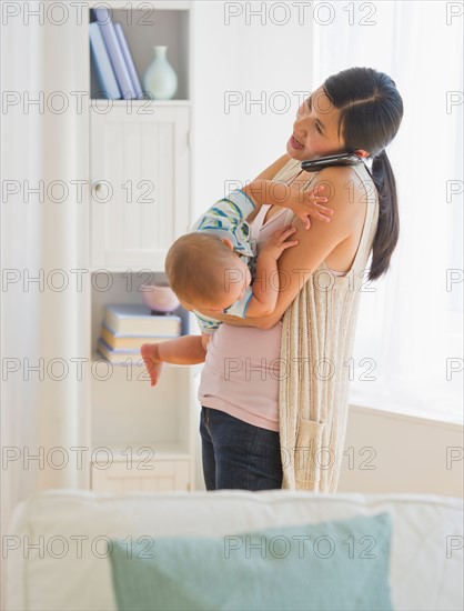Mother carrying son (6-11 months) and talking on phone. Photo : Daniel Grill