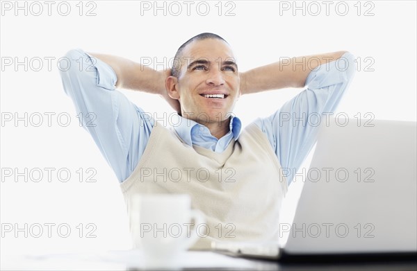 Cheerful office worker with hands behind back. Photo : Momentimages