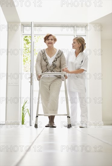 Nurse assisting patient in corridor of clinic. Photo : Momentimages