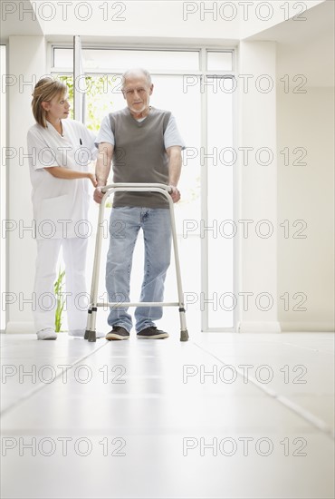 Nurse assisting patient in corridor of clinic. Photo : Momentimages