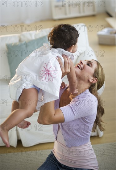 Mother and daughter (12-18 months) playing in living room.