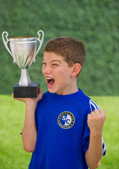 Boy (10-11) holding trophy and cheering. Photo : Daniel Grill