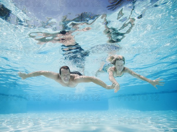 Mid adult couple swimming underwater.