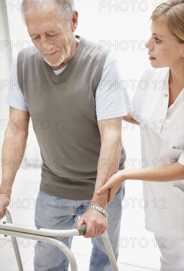 Nurse assisting patient in corridor of clinic. Photo : Momentimages