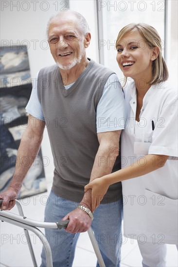 Nurse assisting patient in corridor of clinic. Photo : Momentimages