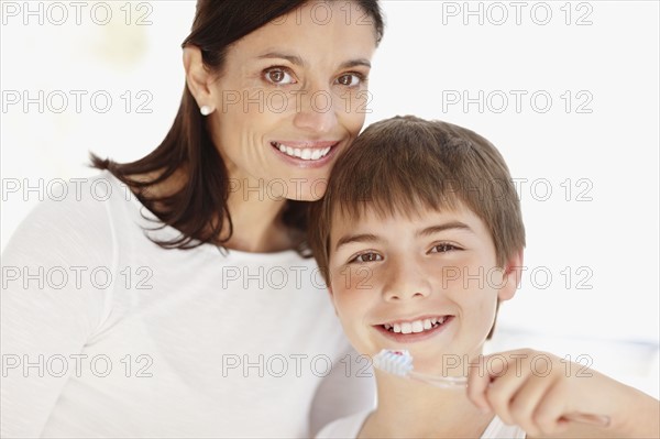 Mother embracing son (12-13)  while he is brushing teeth. Photo : Momentimages