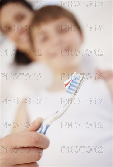 Mother embracing son (12-13) while he is brushing teeth. Photo : Momentimages