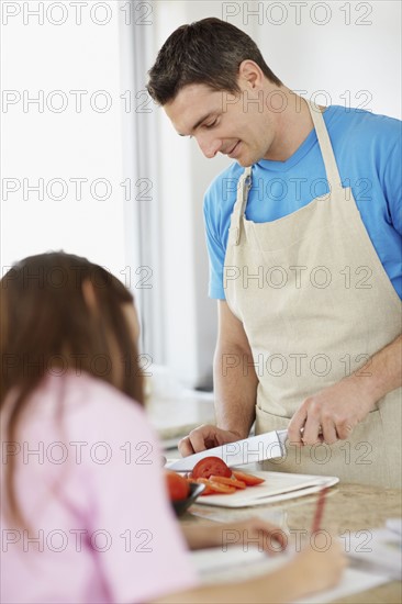 Daughter (10-11) helping father prepare meal . Photo : Momentimages