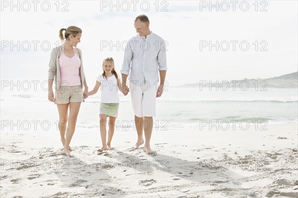 Girl (10-11) playing on beach with parents. Photo : Momentimages