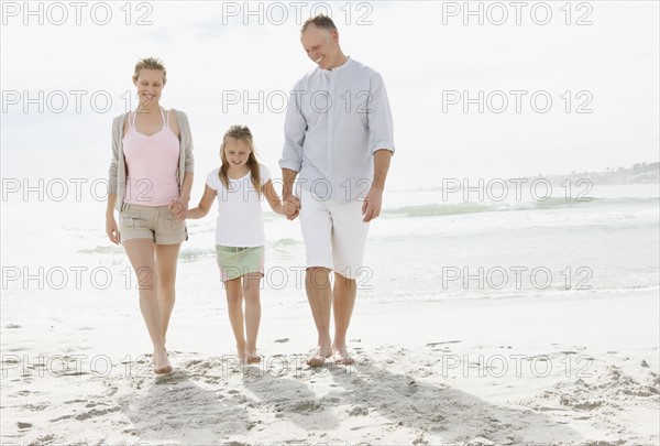 Girl (10-11) playing on beach with parents. Photo : Momentimages