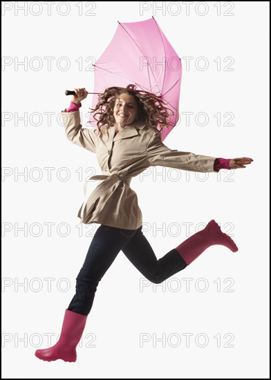 Woman with umbrella jumping on white background. Photo : Mike Kemp