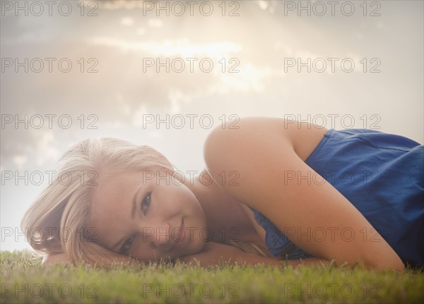 Young girl (16-17) lying on grass. Photo : Mike Kemp