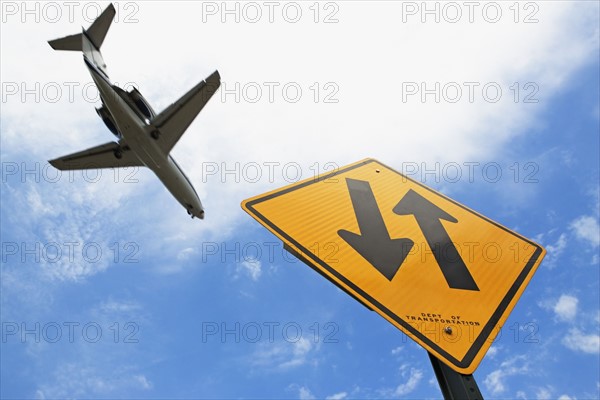 Airplane flying above down traffic sign. Photo : fotog