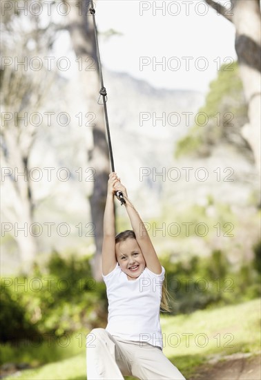 Girl (10-11) swinging on rope. Photo : Momentimages
