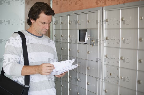 Man standing next to mailboxes and checking post.