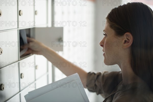 Woman taking letters from mailbox.