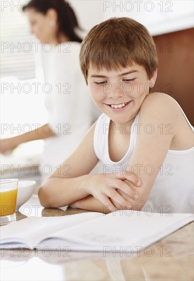 Boy (12-13) sitting over homework with glass of orange juice. Photo : Momentimages