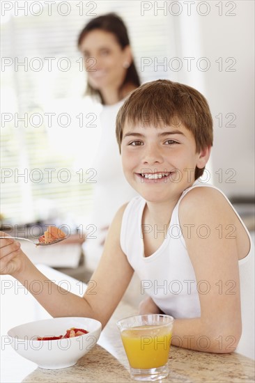 Boy (12-13) with dessert and glass of range juice. Photo : Momentimages