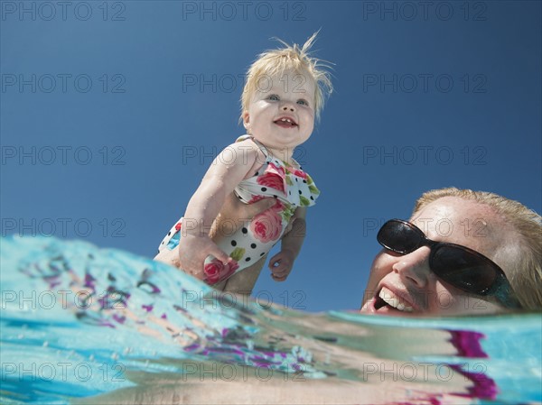 Mother and daughter (12-18months) playing at swimming pool.