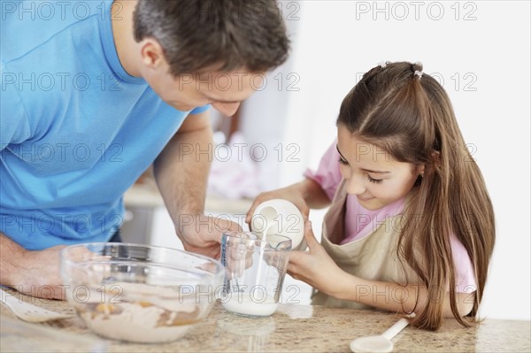 Daughter (10-11) helping father prepare food. Photo : Momentimages