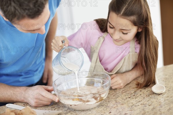 Daughter (10-11) helping father prepare food. Photo : Momentimages