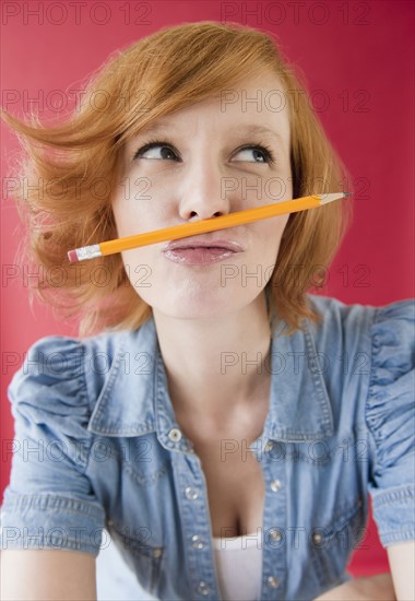 Young woman playing with pencil. Photo : Jamie Grill