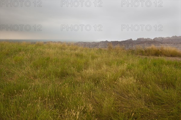 USA, South Dakota, Stormy clouds over prairie grass in Badlands National Park.