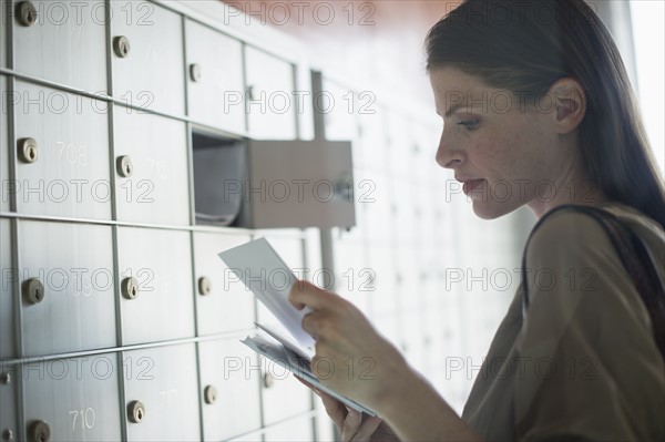 Woman taking letters from mailbox.