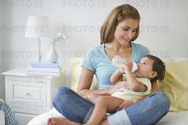 Mother feeding baby daughter (12-18 months) .