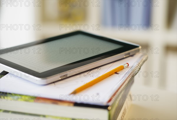 Digital tablet on stack of books.