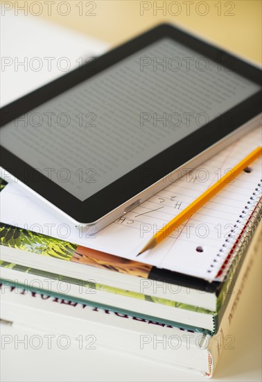 Digital tablet on stack of books.