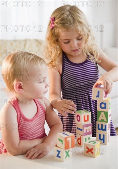 Girls (18-23 months, 4-5) playing with blocks and looking at camera. Photo : Jamie Grill