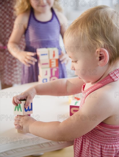 Girls (18-23 months, 4-5) playing with blocks and looking at camera. Photo : Jamie Grill