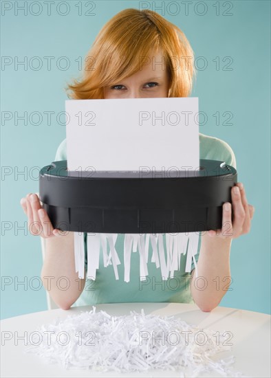 Young woman shredding paper. Photo : Jamie Grill