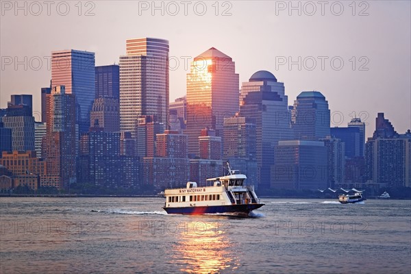 USA, New York State, New York City, Ferry on river and World Financial Center at sunset. Photo : fotog