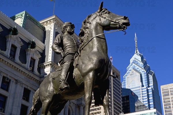 USA, Pennsylvania, Philadelphia, Statue depicting man on horse, skyscrapers in background. Photo : fotog