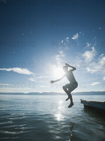 Boy (10-11) jumping from raft.