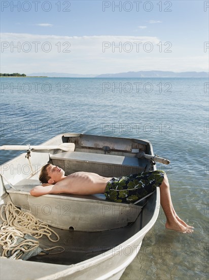 Boy (10-11) resting on boat.