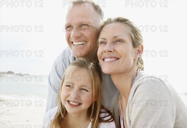 Girl (10-11) playing on beach with parents. Photo : Momentimages