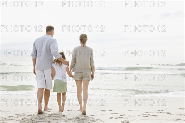 Girl (10-11) playing on beach with parents. Photo : Momentimages