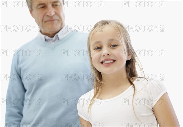 Portrait of happy girl (10-11)grandfather in background. Photo : Momentimages