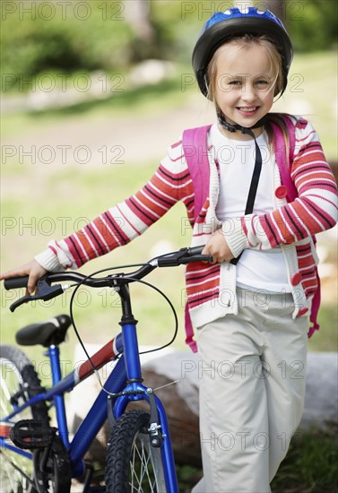 Smiling girl (10-11) with bicycle. Photo : Momentimages