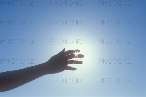 Silhouette of woman's hand against sky. Photo : Chris Hackett