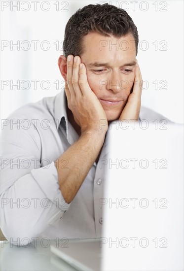 Portrait of good-looking mid adult man working on laptop. Photo : Momentimages