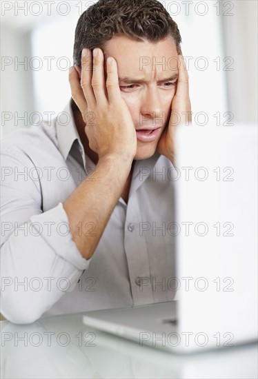 Portrait of good-looking mid adult man working on laptop. Photo : Momentimages