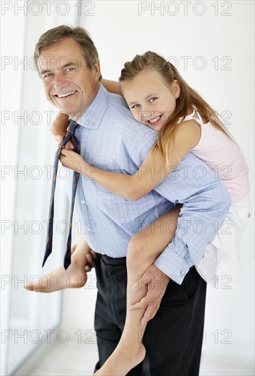 Father carrying girl (10-11) on back. Photo : Momentimages