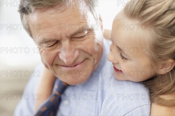 Smiling grandfather and granddaughter (10-11). Photo : Momentimages