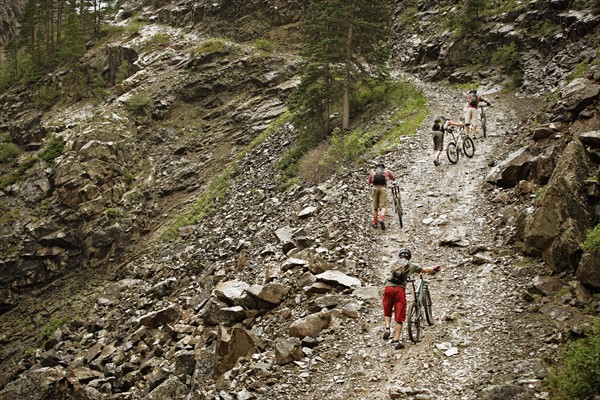 Mountain bikers pushing bikes up hill. Photo : Shawn O'Connor